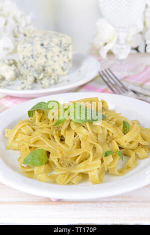 Délicieux plats de pâtes au pesto sur la plaque sur la table sur un fond clair Banque D'Images