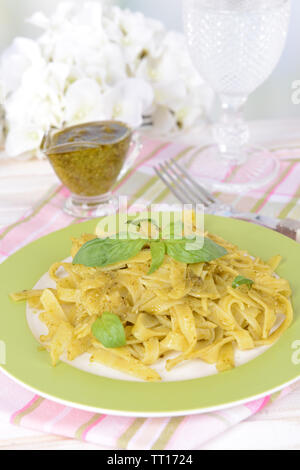 Délicieux plats de pâtes au pesto sur la plaque sur la table sur un fond clair Banque D'Images