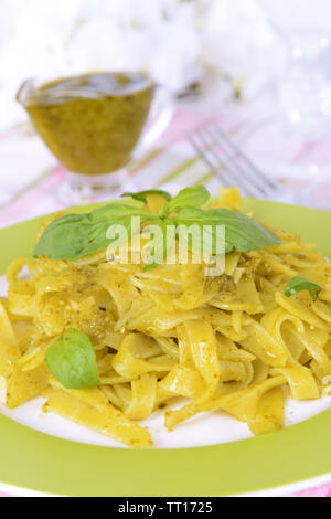 Délicieux plats de pâtes au pesto sur la plaque sur la table sur un fond clair Banque D'Images