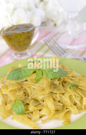 Délicieux plats de pâtes au pesto sur la plaque sur la table sur un fond clair Banque D'Images