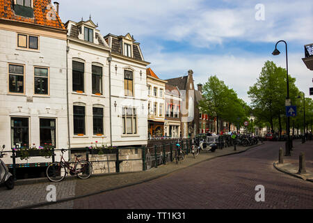 Gouda, Hollande, Pays-Bas, Avril 23, 2019, vélos et stationné près d'un pont le long d'une rue, canal à Gouda vieille ville. Parterres de fleurs dans un bateau, Banque D'Images