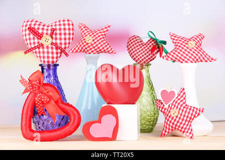 Coeurs textiles faits à la main dans des vases sur table en bois, sur un fond clair Banque D'Images