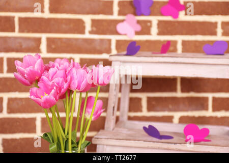 La composition avec bouquet de tulipes dans un vase, sur l'échelle, sur fond de mur Banque D'Images