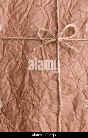 String tied in bow sur brown paper packaging close-up Banque D'Images