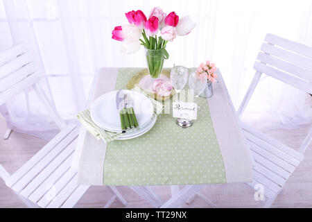 Nouvelle table et chaises avec des couverts sur fond clair Banque D'Images