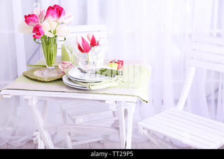 Nouvelle table et chaises avec des couverts sur fond clair Banque D'Images