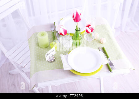 Nouvelle table et chaises avec des couverts sur fond clair Banque D'Images