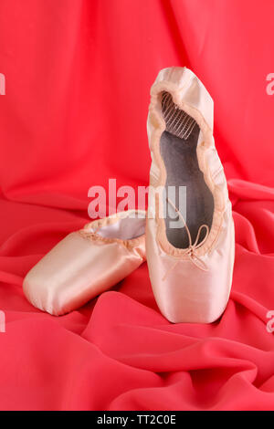 Des chaussons de ballet sur fond de tissu rouge Banque D'Images