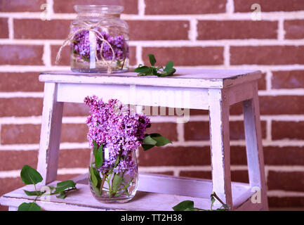 Belles fleurs lilas dans un vase, sur l'échelle en bois, sur fond de mur de couleur Banque D'Images