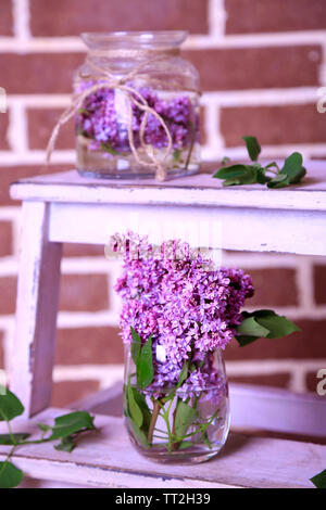 Belles fleurs lilas dans un vase, sur l'échelle en bois, sur fond de mur de couleur Banque D'Images