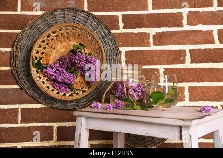 Belles fleurs lilas dans un vase, sur l'échelle en bois, sur fond de mur de couleur Banque D'Images