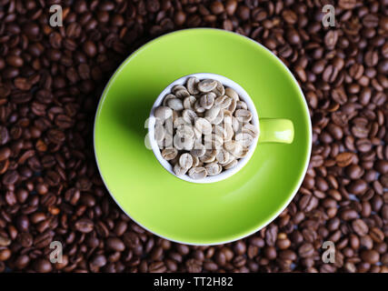 Tasse pleine de café vert sur fond brun café en grains Banque D'Images