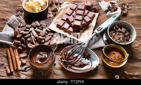 Les fèves de cacao, poudre de cacao, beurre, chocolat et sauce au chocolat sur fond de bois Banque D'Images