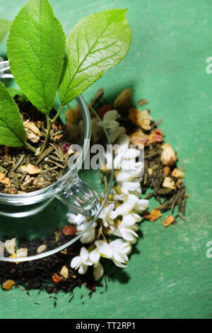 Tasse en verre avec des fleurs et d'herbes sèches, de fruits Ingrédients pour le thé, sur la couleur de fond de bois Banque D'Images