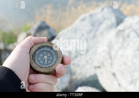 La main de l'homme est titulaire d'une boussole contre les rochers par temps ensoleillé. Banque D'Images