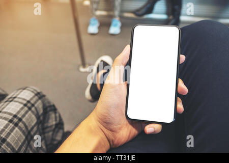 Image d'une maquette man's hand holding black téléphone mobile avec écran vide dans le métro Banque D'Images