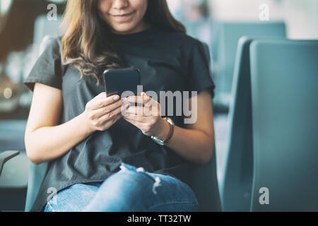 Une femme à l'aide de téléphone portable en voyageur assis dans l'aéroport Banque D'Images