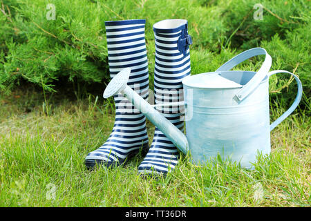 Des bottes en caoutchouc avec arrosoir sur l'herbe - concept de jardinage Banque D'Images