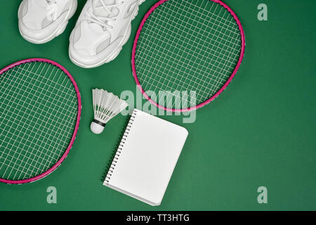 Sports Télévision coucha avec volant et raquette de badminton, tennis et bloc-notes sur fond vert. Sport, remise en forme et d'un style de vie sain concept. Banque D'Images