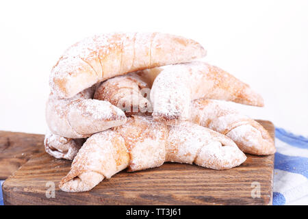 Bagels savoureux avec du sucre en poudre sur planche de bois, isolé sur blanc Banque D'Images