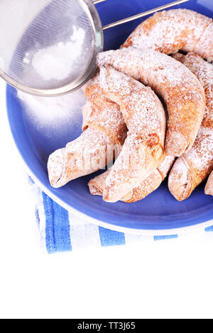 Bagels savoureux avec du sucre en poudre sur plaque, isolated on white Banque D'Images