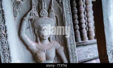 Détail d'une sculpture antique avec un corridor flou en arrière-plan dans la diminution de la perspective dans le magnifique temple Bayon - un Khmer décoration Banque D'Images