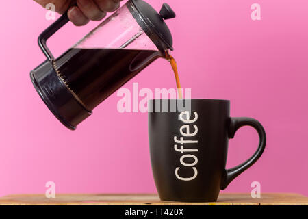 Verser du café frais int un mug d'une cafetière. Banque D'Images