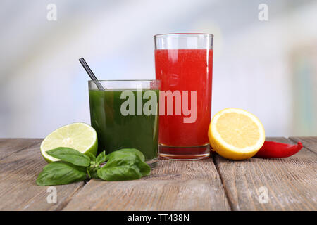 Verres de jus de légumes avec lime et citron sur table en bois Banque D'Images