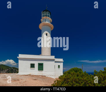Big White lighthouse tower building debout sur terre rocheux et sablonneux avec ciel bleu profond dans l'arrière-plan Banque D'Images