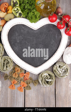 Composition des pâtes colorées, tomates fraîches, persil sur fond de bois Banque D'Images