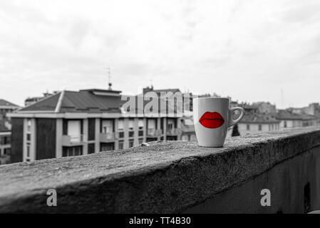 Une tisane tasse décorée d'une lèvre rouge motif, sur le seuil d'un balcon, couleur sélective Banque D'Images