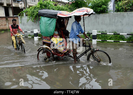 Guwahati, Assam, Inde. 14 juin, 2019. Les banlieusards patauger dans une rue gorgé d'eau après de fortes pluies dans la région de Guwahati, Assam, Inde le vendredi, Juin 14, 2019. Crédit : David Talukdar Alamy Live News Banque D'Images