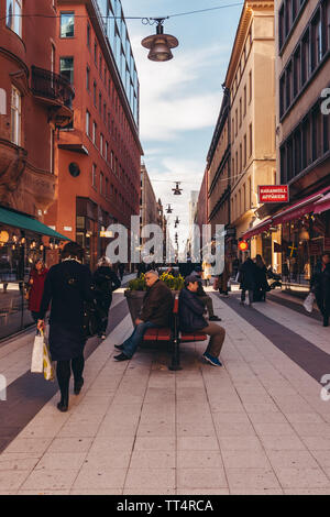 Editorial 27.03.2019 Stockholm Suède. Des gens assis sur un banc sur Drottning gatan street un jour de printemps avec le soleil Banque D'Images