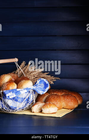 Petits pains savoureux avec du sésame dans le panier, sur la couleur de fond de bois Banque D'Images