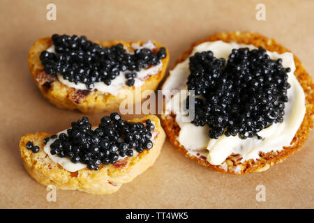 Tranches de pain avec du beurre et de caviar noir sur fond de papier Banque D'Images