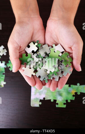 Pièce du puzzle dans les mains sur fond de table en bois Banque D'Images