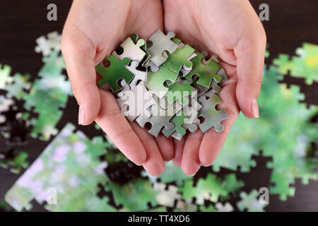 Pièce du puzzle dans les mains sur fond de table en bois Banque D'Images