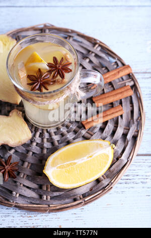 Tasse de boisson au gingembre avec du citron sur le tapis en osier sur fond de bois Banque D'Images