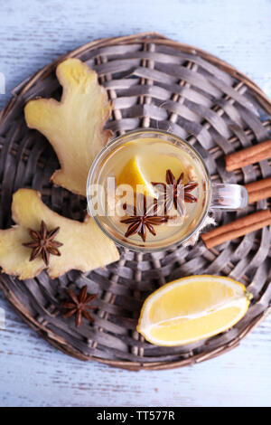 Tasse de boisson au gingembre avec du citron sur le tapis en osier sur fond de bois Banque D'Images