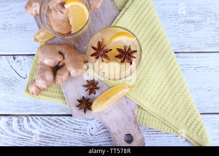 Verres de boisson au gingembre avec du citron sur serviette sur une planche à découper sur fond de bois Banque D'Images