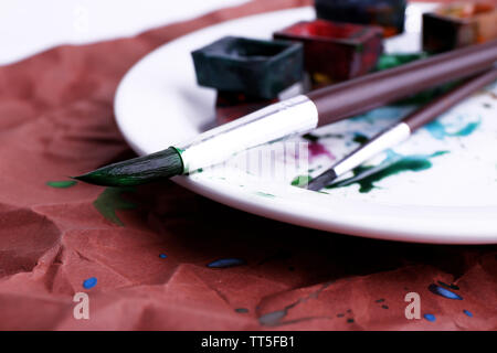 Peinture à l'aquarelle avec des pinceaux cubes sur plaque sur fond de papier brun Banque D'Images