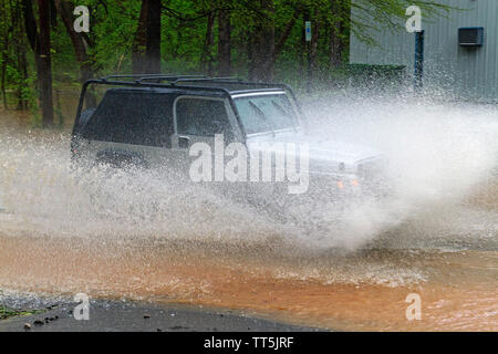 Une voiture de manière explosive par les éclaboussures d'eau dangereusement élevé sur une route inondée de la rivière Banque D'Images