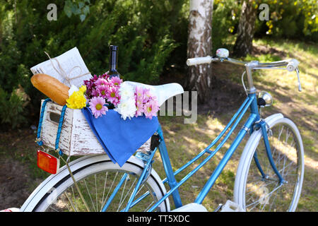 Location avec des fleurs, du pain et une bouteille de vin dans la boîte en bois sur fond d'herbe Banque D'Images