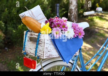 Location avec des fleurs, du pain et une bouteille de vin dans la boîte en bois sur fond d'herbe Banque D'Images