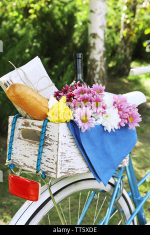 Location avec des fleurs, du pain et une bouteille de vin dans la boîte en bois sur fond d'herbe Banque D'Images