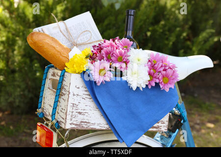 Location avec des fleurs, du pain et une bouteille de vin dans la boîte en bois sur fond d'herbe Banque D'Images