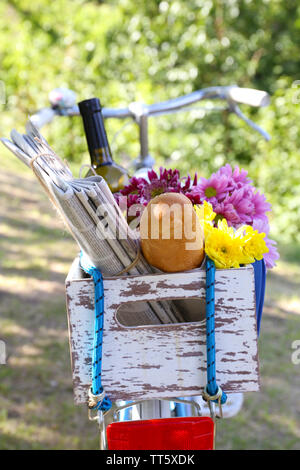 Location avec des fleurs, du pain et une bouteille de vin dans la boîte en bois sur fond d'herbe Banque D'Images