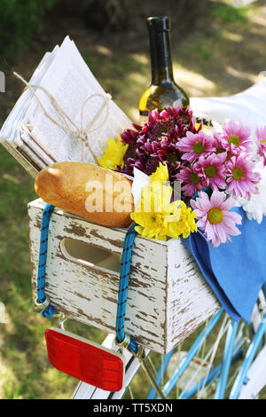 Location avec des fleurs, du pain et une bouteille de vin dans la boîte en bois sur fond d'herbe Banque D'Images