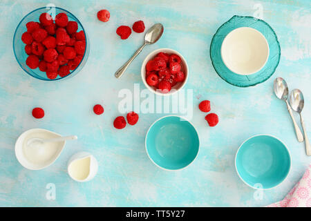 Frais de la berry patch framboises rouges mûrs avec aqua et blanc sur fond de bois plats rustiques. Coup de frais généraux dans la composition des plats. Banque D'Images