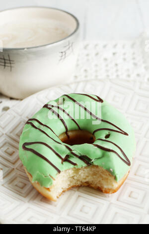 Mordu de délicieux donut sur plaque sur table en bois close-up Banque D'Images